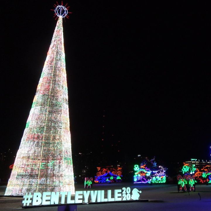 luces navideñas llenas de árboles altos letreros con luces que dicen bentleyville 2020 y un letrero que dice gracias a nuestras tropas