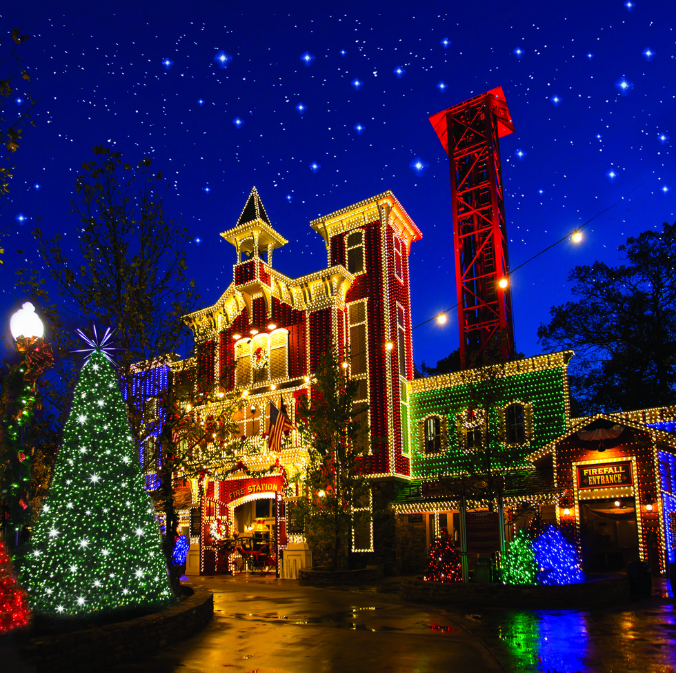Luces navideñas en un edificio antiguo de tres pisos con otros edificios iluminados al lado y árboles de Navidad decorados al otro lado de la calle