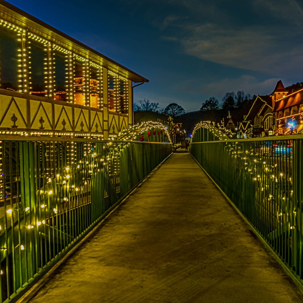Puente con luces blancas al lado de edificios alpinos con apariencia de pueblo líneas en luz blanca