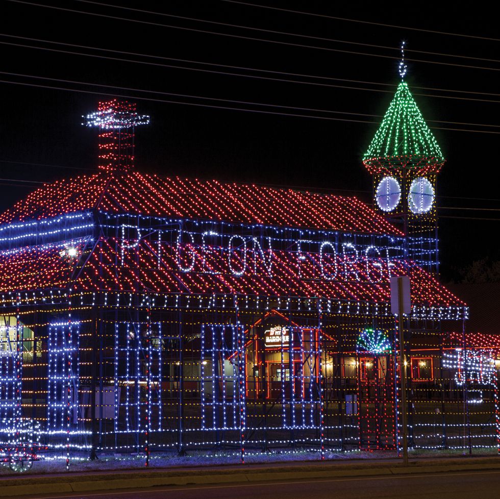 edificio delineado con luces rojas y blancas, con palomas escritas y también una torre de reloj con luces verdes en el techo
