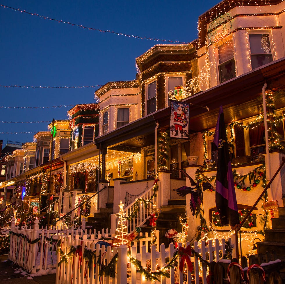 Casas adosadas decoradas para Navidad con luces brillantes y vegetación navideña.